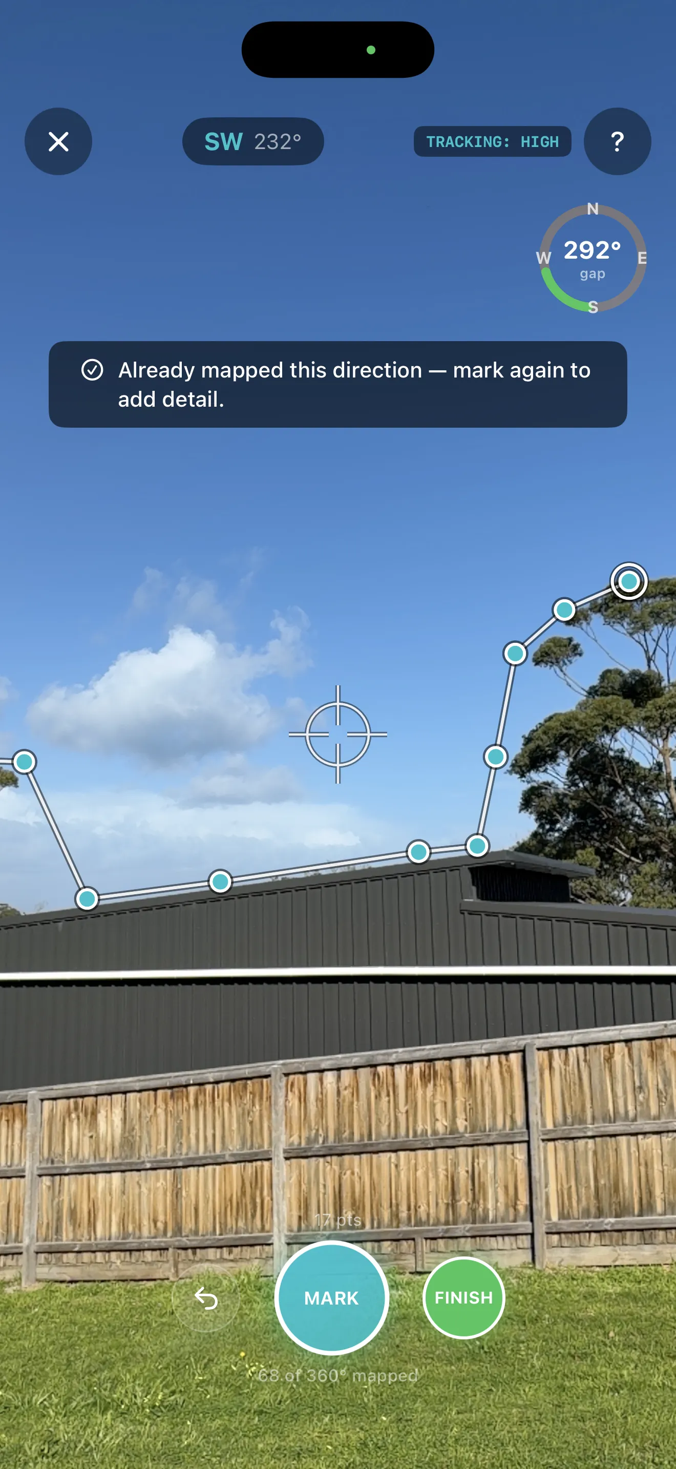 Sky Profile capture screen mid-capture: a white line traces a shed roofline and tree canopy, with teal points already marked, a crosshair marks where the phone is aimed now, a compass heading and 'TRACKING: HIGH' badge sit at top, a readout shows how many of 360 degrees are mapped, and a dark banner reads 'Already mapped this direction — mark again to add detail.'